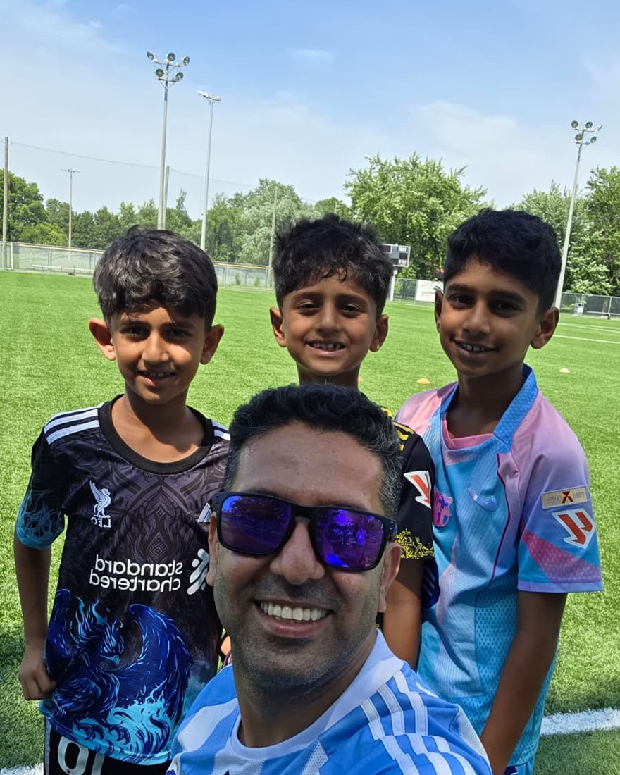 Coach Reza with young players on an outdoor field