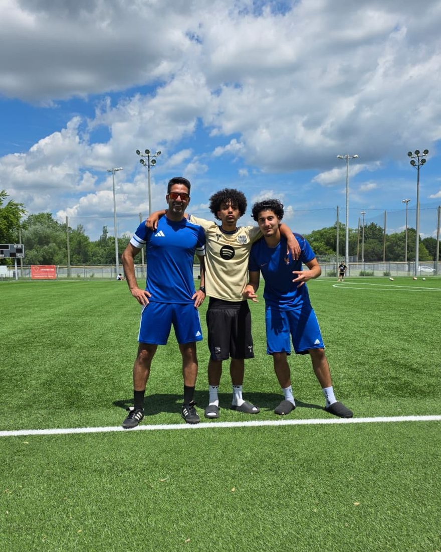 Coach Reza with two players on the field